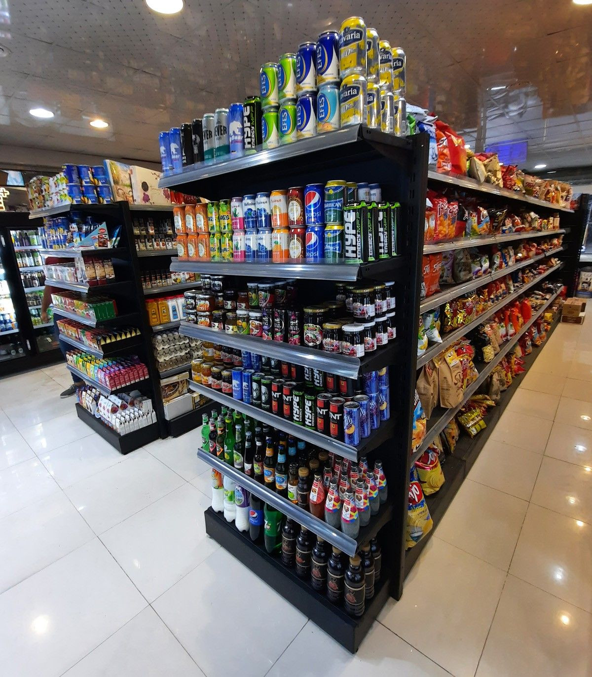 قفسه فلزی وسط فروشگاهی با محصولات متنوع در سامان انبار شرق طوس، فضایی منظم و جذاب برای مشتریان.