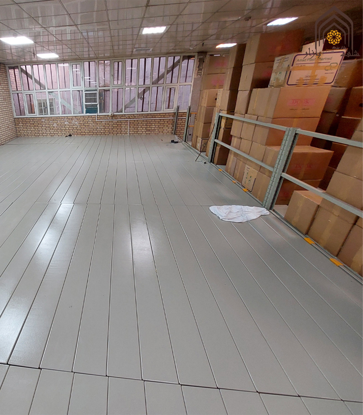 نیم طبقه راک بالکن با کفپوش چوبی و دیوارهای کارتن، فضایی روشن و کارآمد برای استفاده‌های مختلف.