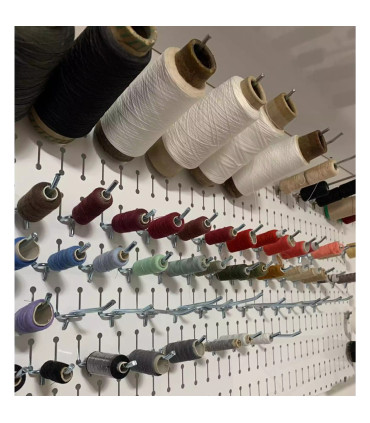 پگ برد حرفه ای با مجموعه ای از رنگ های متنوع نخ در یک دیوار نصب شده. این ابزار برای خیاطی و صنایع دستی ضروری است.